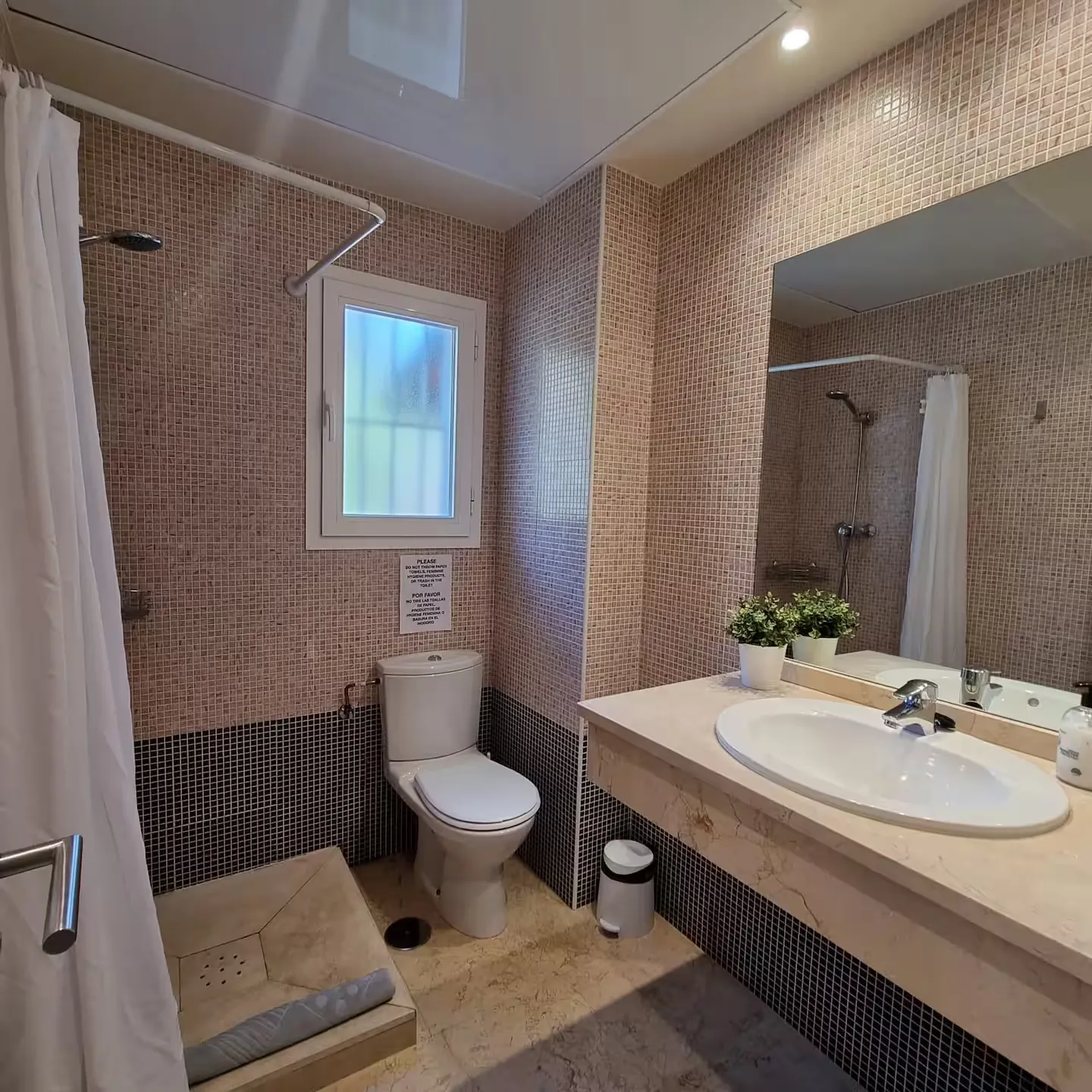 Baño con ducha, inodoro y lavabo con espejo