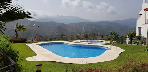 Dos piscinas comunitarias rodeadas de césped con vistas a la sierra