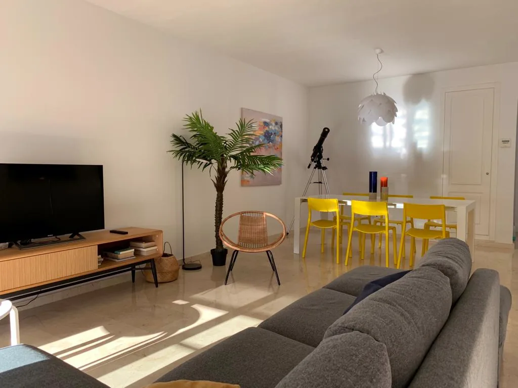 Salón con sofá, mesa de comedor y luz natural