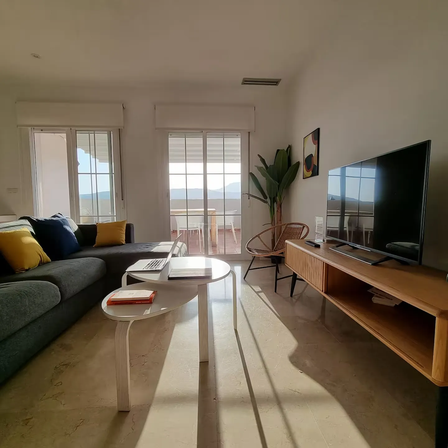 Salón con sofá, televisión y salida a la terraza