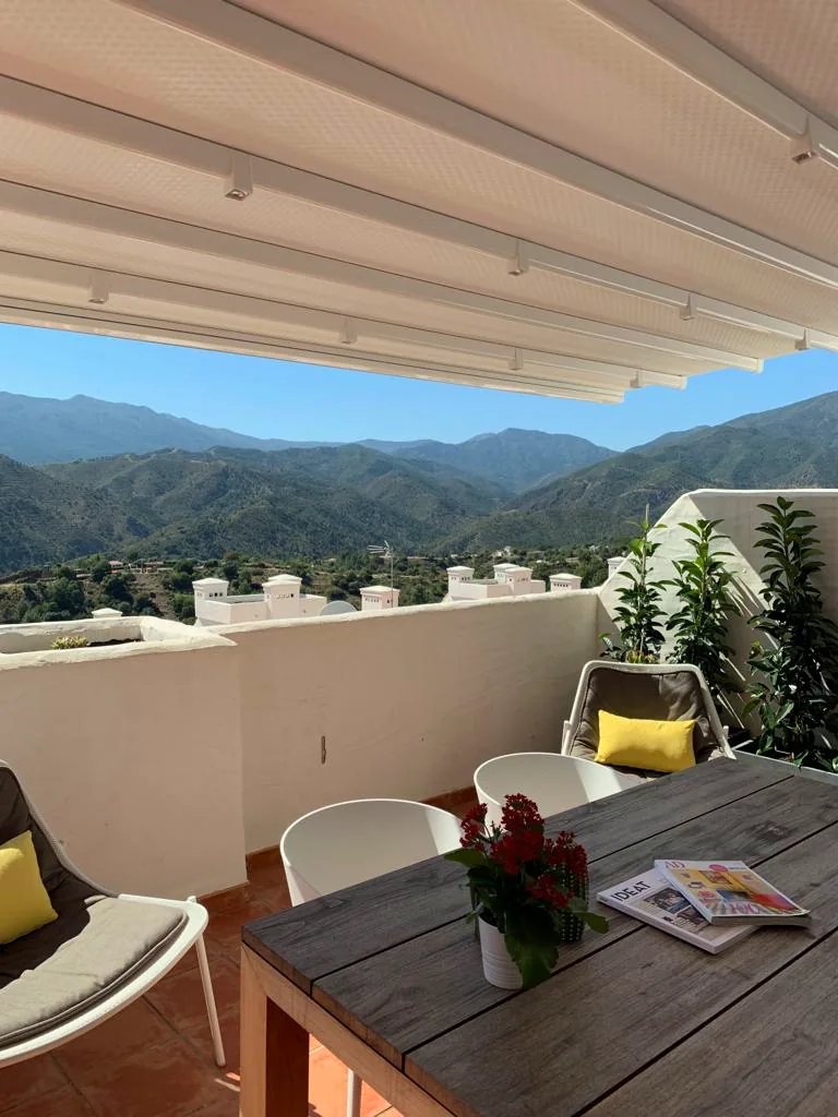 Terraza con mesa y sillas frente a las montañas